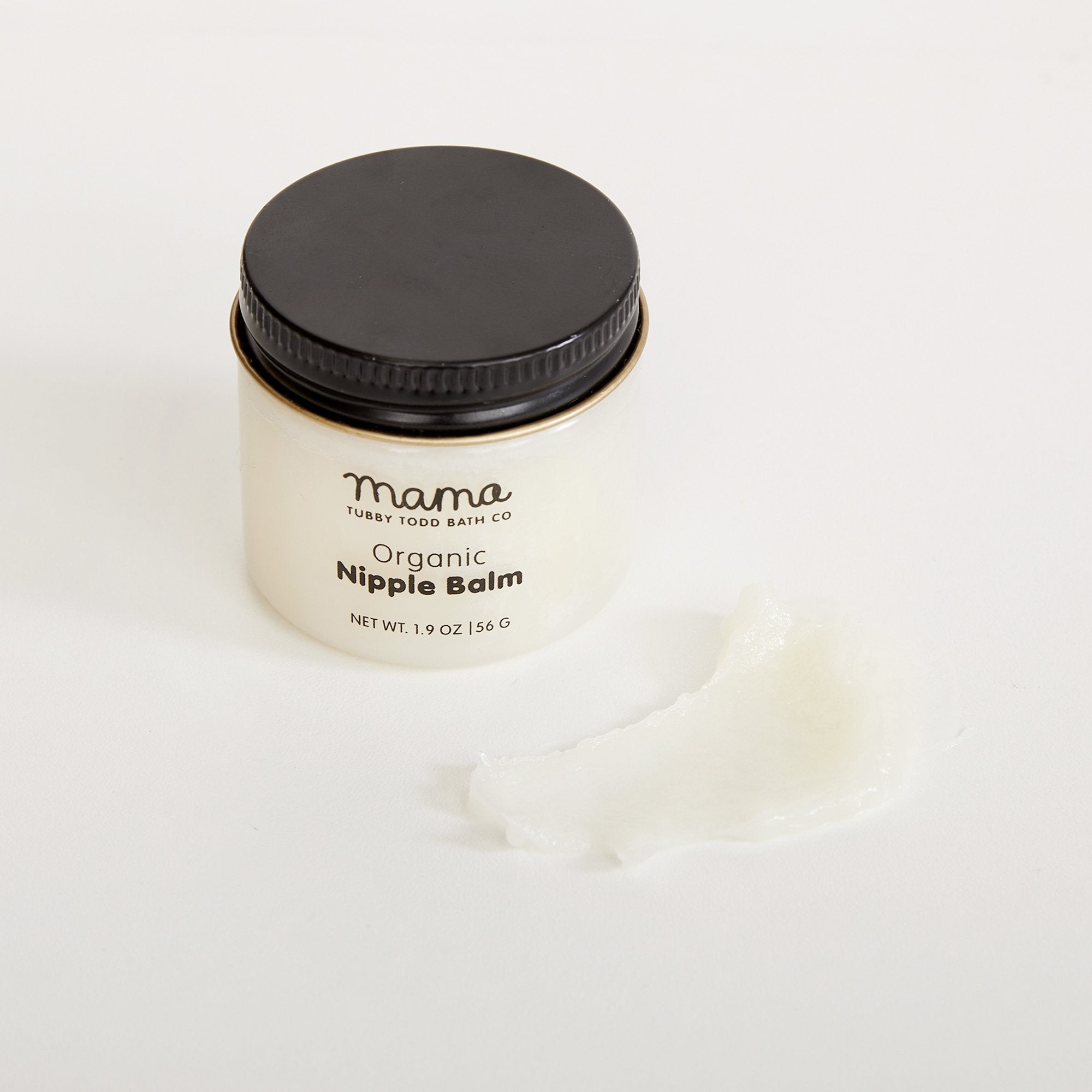 Nipple balm jar next to a small amount of balm on table to show texture